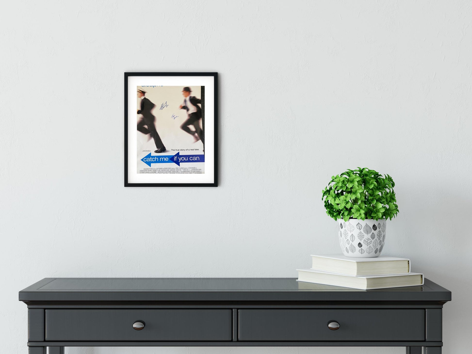 a black table with a plant and a white wall